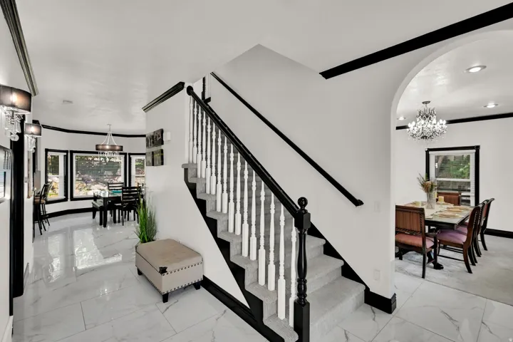 Central staircase with black wood newel post and balusters, white spindles, and carpeted treads