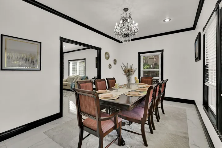 Formal dining room featuring white walls with contrasting black trim, elegant chandelier lighting, recessed ceiling lighting, and large format tile flooring