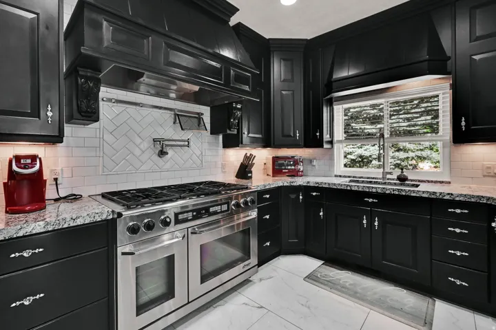 Kitchen featuring black cabinetry, stainless steel range, white subway tile backsplash, granite countertops, and recessed lighting