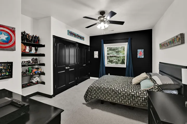 Bedroom featuring a ceiling fan with integrated lighting, a window with exterior views, and a dedicated accent wall