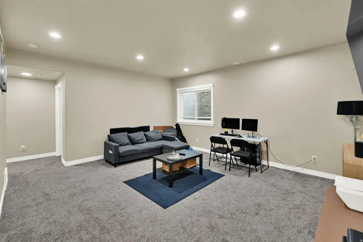 Spacious room featuring neutral paint, gray carpeting, a window with blinds, recessed lighting, and white baseboards