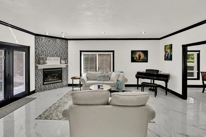 Spacious living area featuring large format marble-look tile flooring, a fireplace with a decorative tile surround and white mantel, and recessed lighting