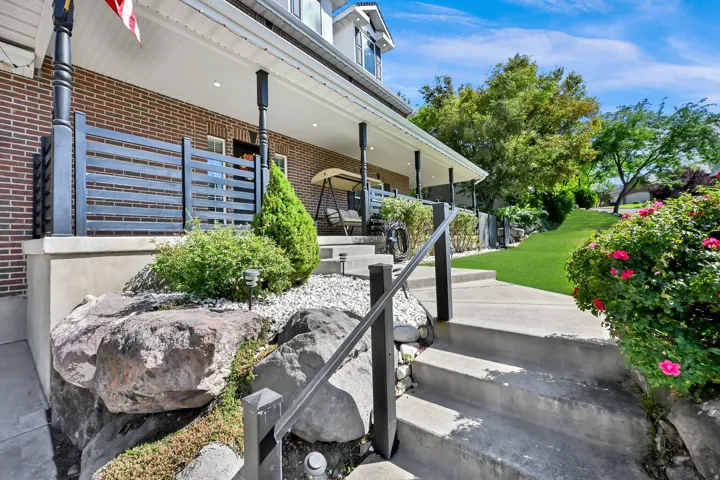 Concrete staircase with metal handrails leading to a brick-faced home with a covered porch