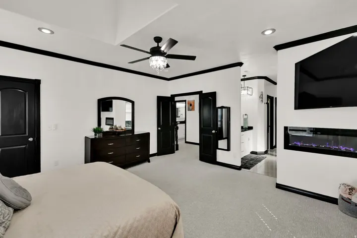 Spacious room featuring light-colored carpeting, white walls with contrasting dark trim, and multiple dark paneled doors