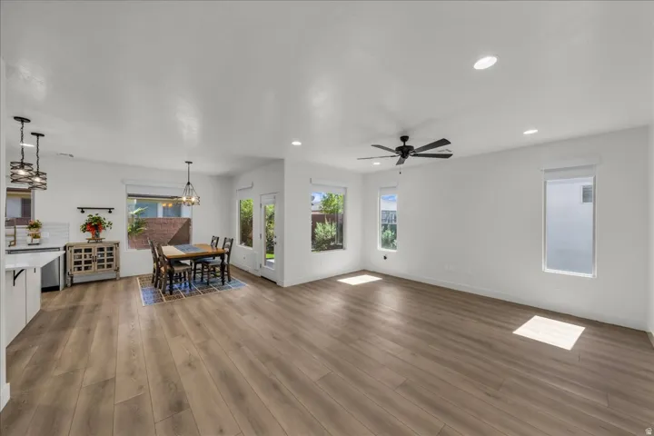 Open-concept living space featuring wood-finish flooring, recessed lighting, and multiple windows with roller shades
