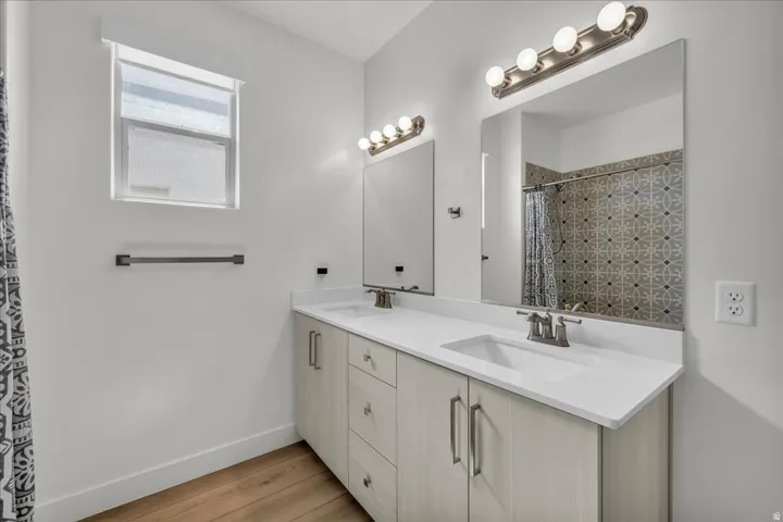 Dual vanity featuring integrated sinks, light-toned wood-finish cabinetry, and quartz countertops