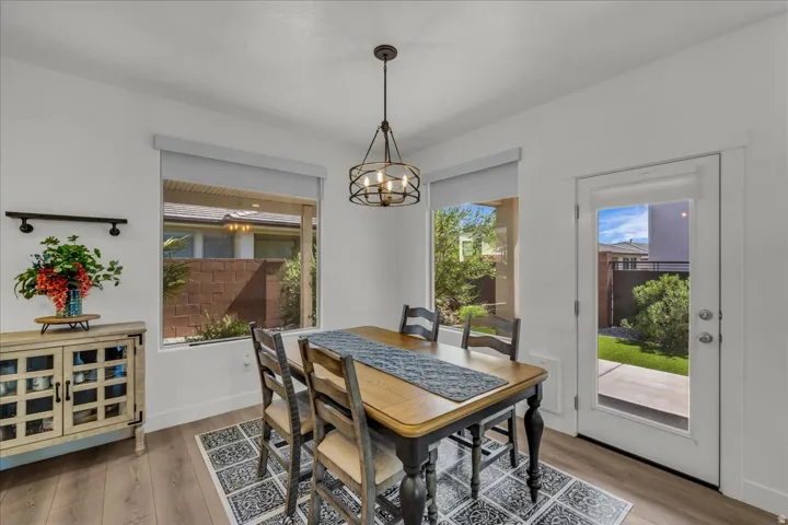 Dining area featuring wood-finish flooring, a contemporary chandelier, and white walls