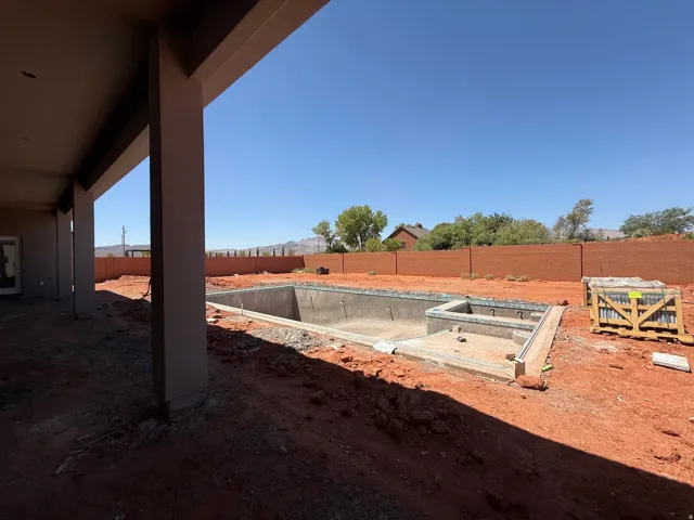 Unfinished rectangular pool with integrated spa and surrounding red earth