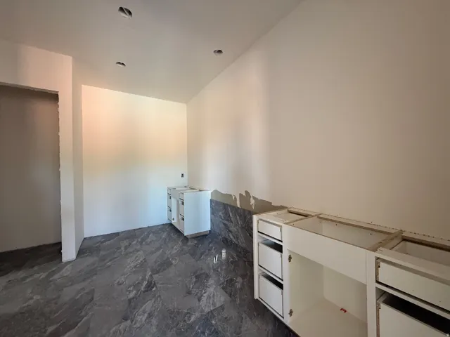 Recessed lighting, tile flooring, white cabinetry, and a dark stone backsplash
