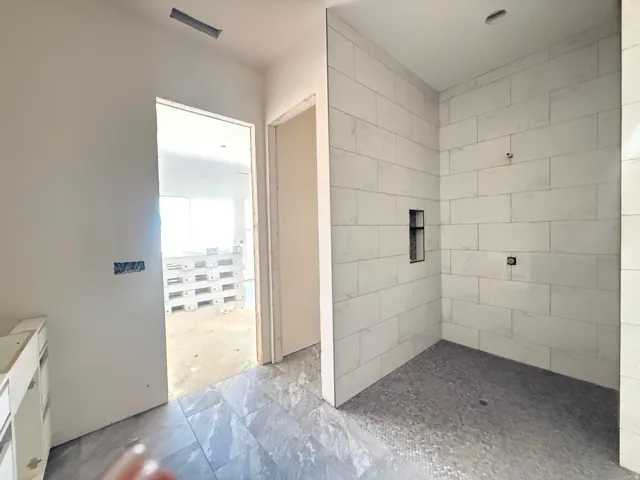 Walk-in shower with large format wall tiling, mosaic floor tiling, and a built-in shower niche