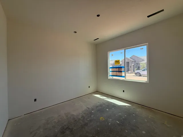Bright, open room featuring recessed ceiling lighting, large picture window with natural light, concrete flooring, and fresh drywall finishes throughout