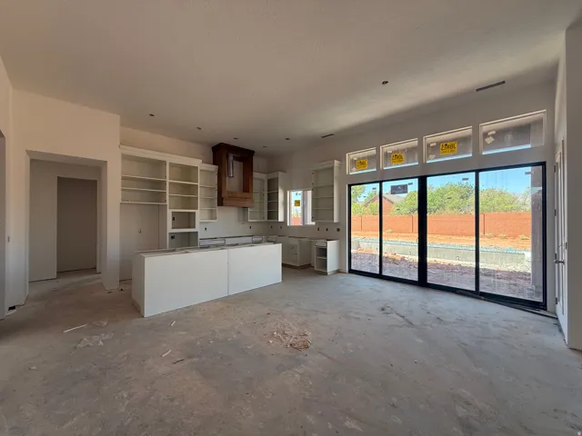 Kitchen featuring white cabinetry with glass-front uppers, a central island, and a wood-finish range hood