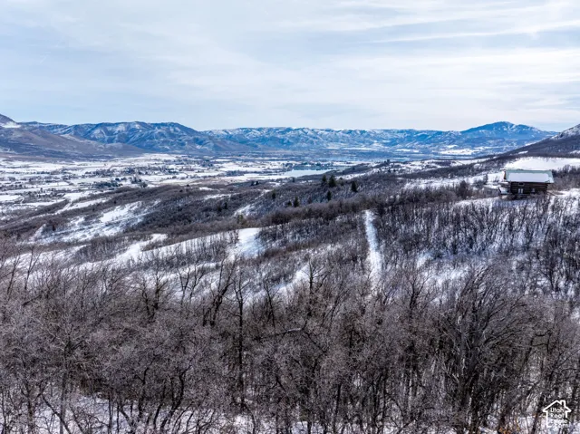 Snow-covered mountain landscape featuring a distant valley and a singular structure
