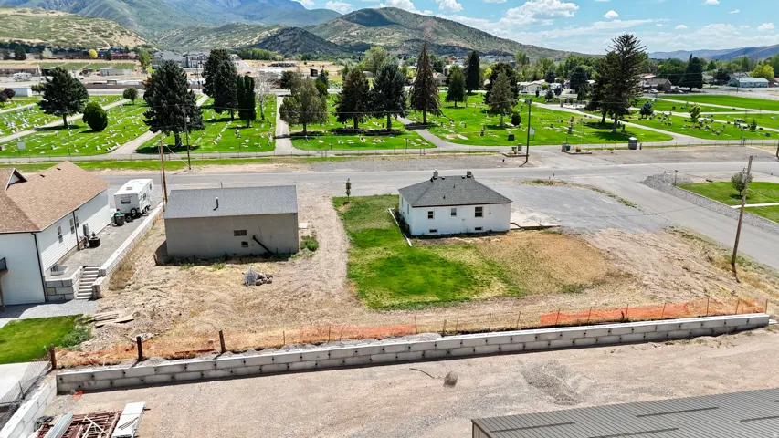 Property featuring two structures, a concrete block retaining wall, and a gravel lot