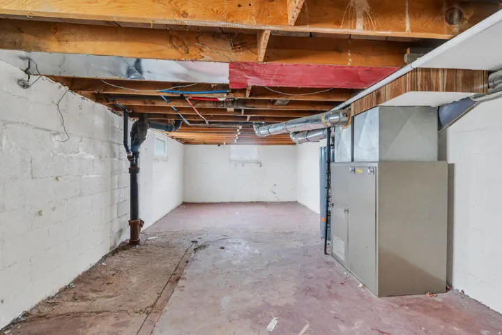 Unfinished basement featuring exposed wood ceiling joists and concrete flooring