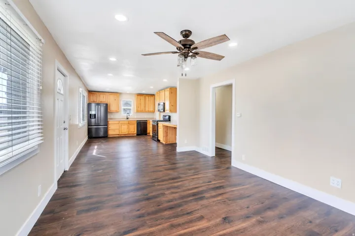 Open-concept living area featuring wood-finish flooring, recessed lighting, and a ceiling fan with integrated lighting