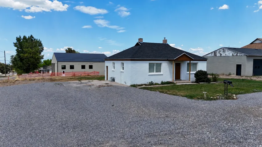 Single-story property featuring a white exterior and dark shingle roof