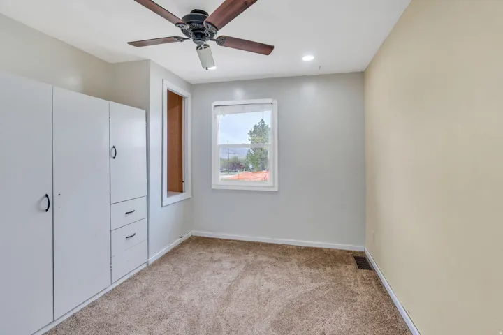 Carpeted room featuring a ceiling fan, recessed lighting, and a window with white trim