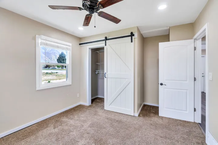 Carpeted room featuring a white-framed window, a ceiling fan, and recessed lighting