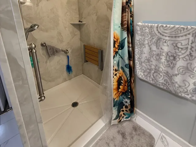 Walk-in shower with a neutral-toned, large-format tile surround and a decorative border
