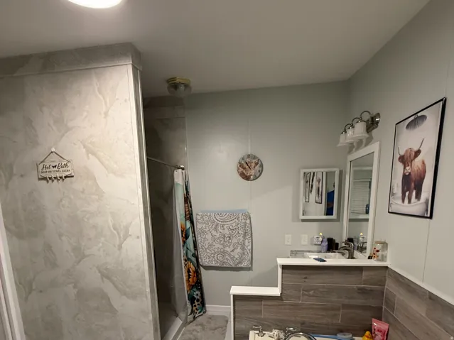 Bathroom featuring a built-in tub, separate shower with stone-look tile, and ceramic tile flooring