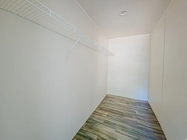 Walk-in closet with wire shelving and wood-finish flooring