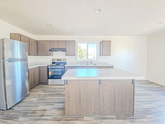 Kitchen featuring stainless steel appliances, wood-finish cabinetry, a central island, recessed lighting, and wood-finish flooring