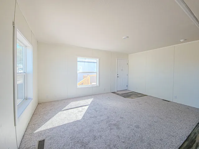 Carpeted flooring, white paneled walls, recessed ceiling lighting, and a white entry door