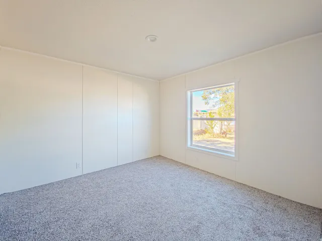 Neutral tone wall panels, recessed ceiling lighting, single pane window, and textured carpet flooring