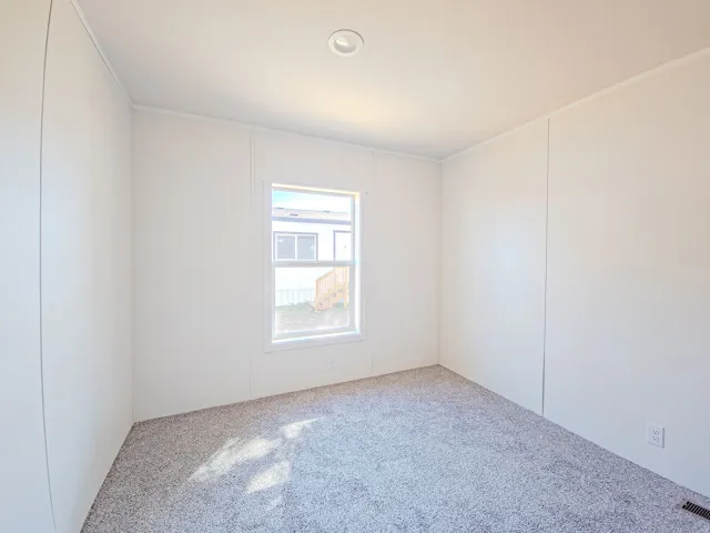 Recessed lighting, neutral wall panels, white trim, window, and gray flecked carpeting