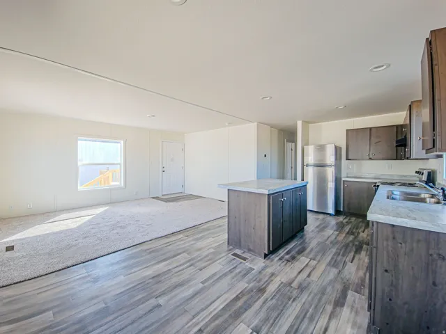 Open-concept living space featuring wood-finish flooring, a kitchen island with storage, stainless steel appliances, and recessed lighting