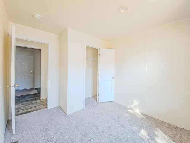 Plush carpet flooring, recessed ceiling lighting, and a bi-fold closet with wire shelving