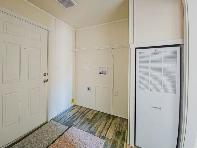 Utility area featuring wood-finish flooring, a white paneled door, and built-in wire shelving