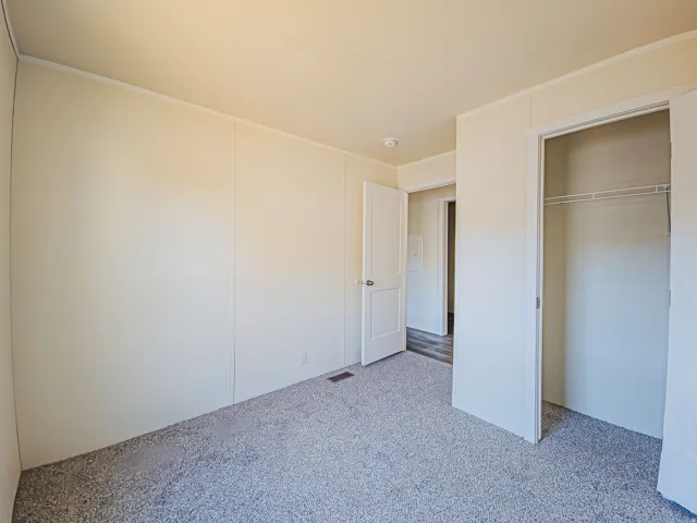 Light-colored walls, textured carpeting, interior door, and a built-in closet with shelving