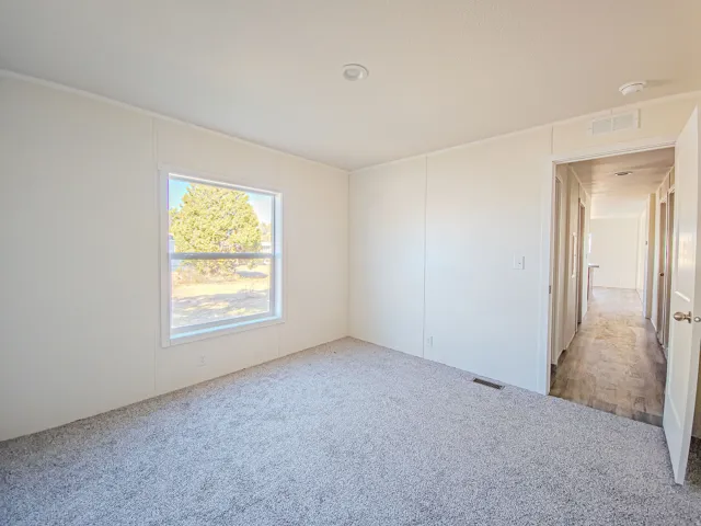 Recessed ceiling light, neutral wall finishes, carpet flooring, window with natural light, and a hallway entrance