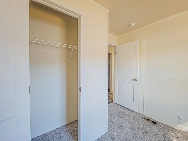 Carpeted room featuring a wire closet shelving system and a solid panel door