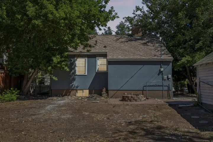 Rear exterior with a pitched roof, multiple windows, and a brick-built fire pit