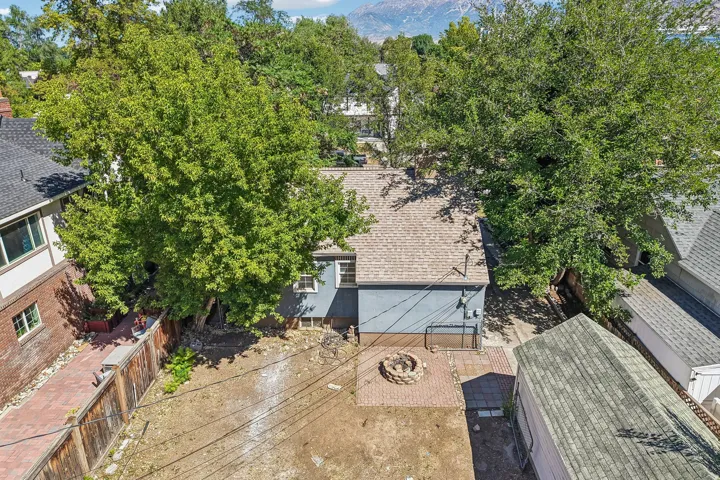 Backyard area featuring a paver patio with a built-in fire pit, a wood privacy fence, and mature trees