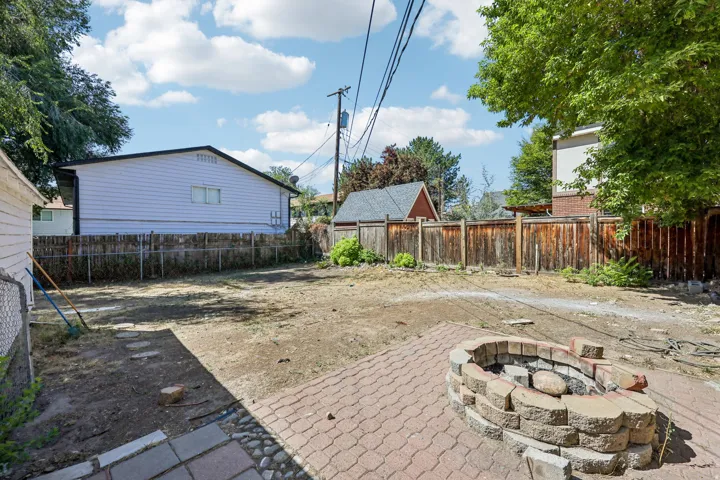 Expansive outdoor area featuring a paver patio and a stone-built fire pit
