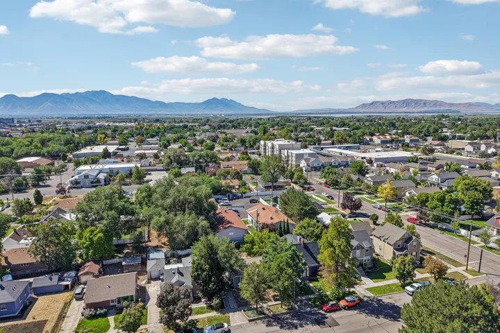 Expansive residential area with mature tree canopies, bordered by distant mountains and a body of water