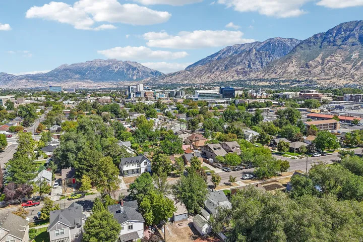Aerial perspective showcasing a residential area with mature trees and mountain scenery