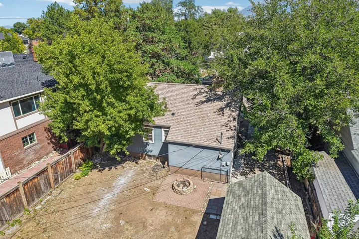 Expansive backyard featuring mature tree canopy, newly installed composite decking, concrete patio space, and an attached two-car garage with modern paneling