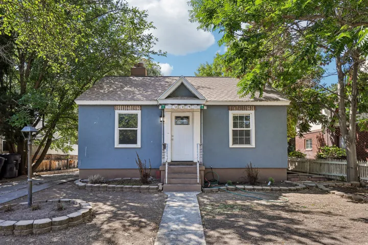 Stucco exterior with brick detailing, asphalt shingle roof, white trim windows, and a concrete pathway