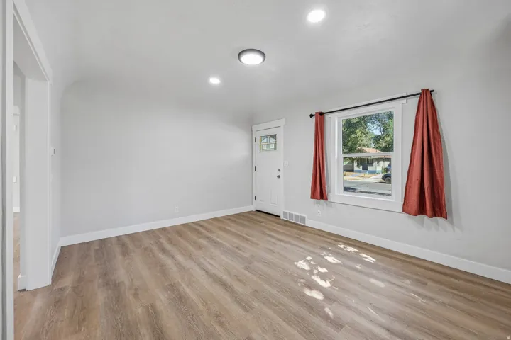 Wood-finish flooring, recessed lighting, white trim, and a white entry door with glass panels