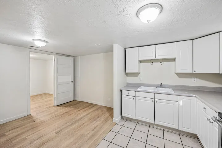 White cabinetry, double basin sink, light-toned countertops, and wood-finish flooring