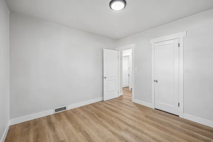 Neutral wall paint, wood-finish flooring, white trim, and a flush-mount ceiling light