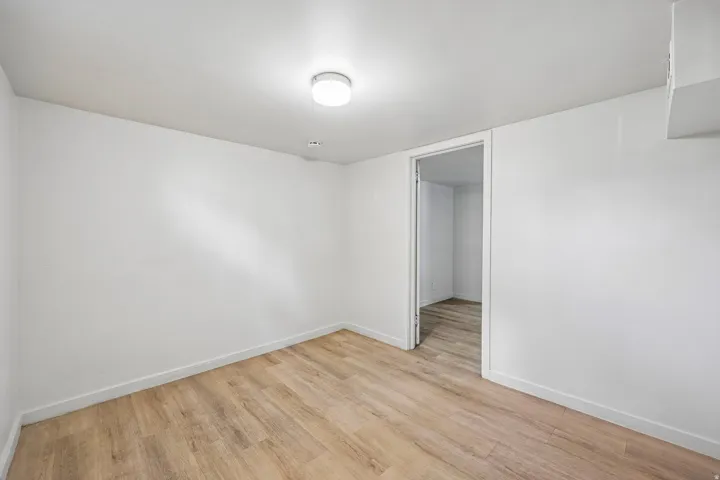 Recessed ceiling light, wood-finish flooring, white walls, and a flush mount ceiling light