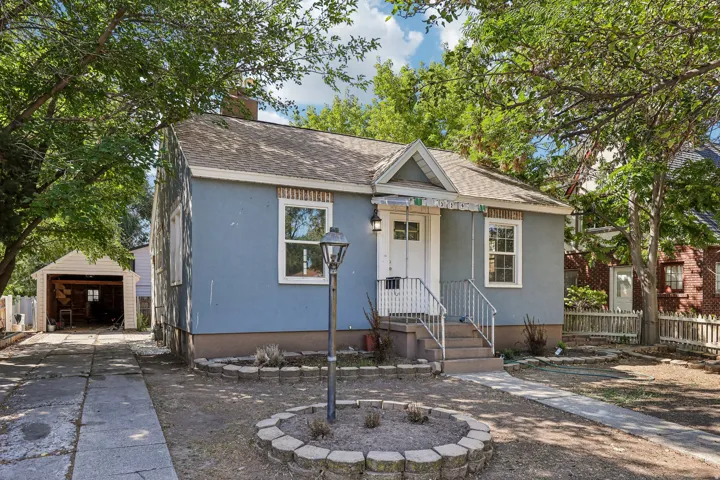 Blue stucco exterior with white trim, covered front porch, and a detached two-car garage