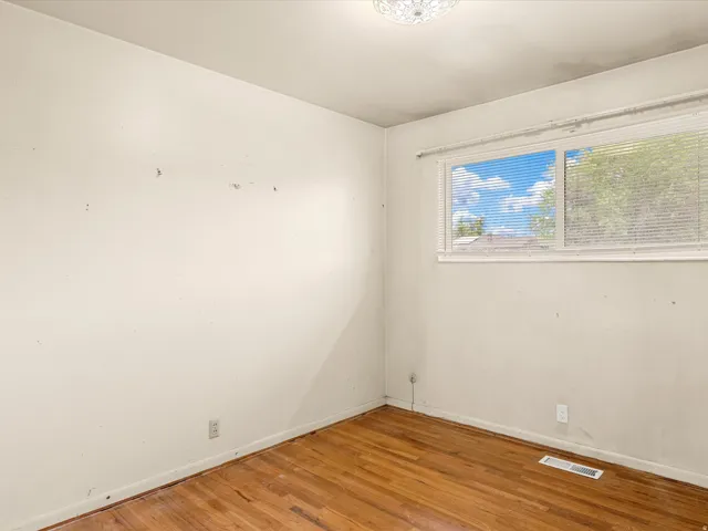 Interior room featuring wood-finish flooring, white walls, and a window with blinds