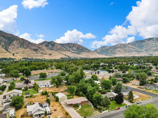 Expansive mountainous backdrop frames a residential area featuring a variety of housing styles and mature landscaping